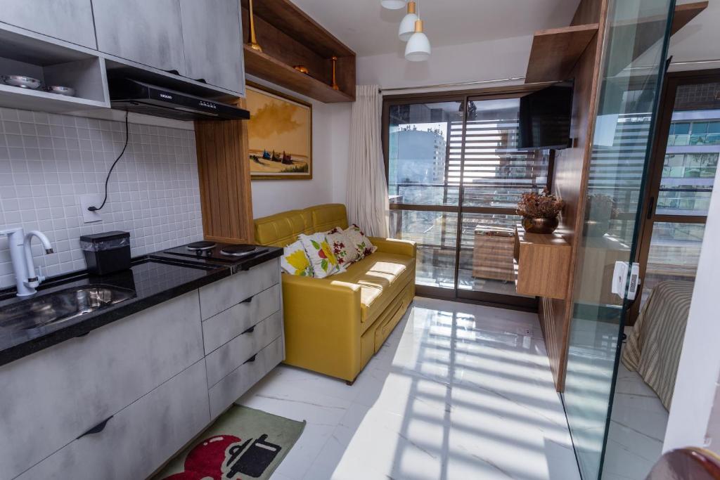 uma cozinha com um sofá amarelo num quarto em Studio Smart Farol da Barra Completo e Funcional em Salvador