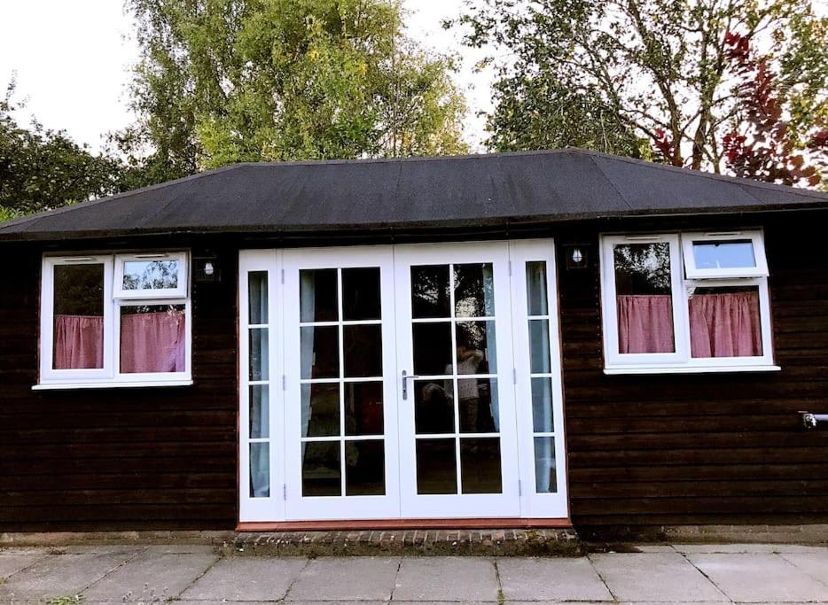 a small house with white doors and windows at Cosy Private Cabin with parking in good location in Oxford