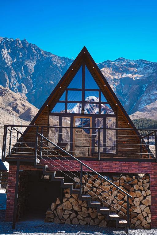 a log cabin with a staircase and mountains in the background at Voyager in Kazbegi