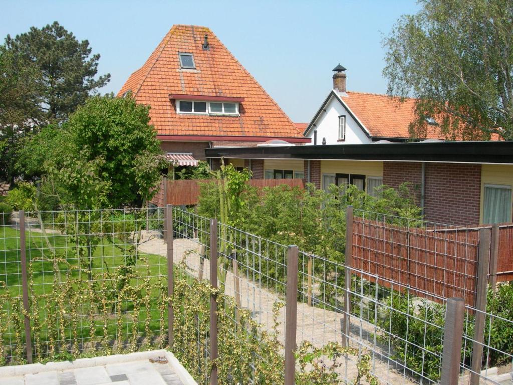 a house with a fence and a building behind it at Pension Kamperland in Kamperland