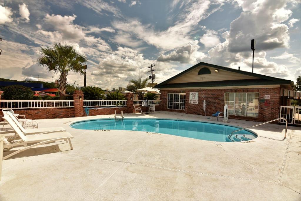 - une piscine avec 2 chaises et une maison dans l'établissement Rodeway Inn Harbison Area, à Columbia