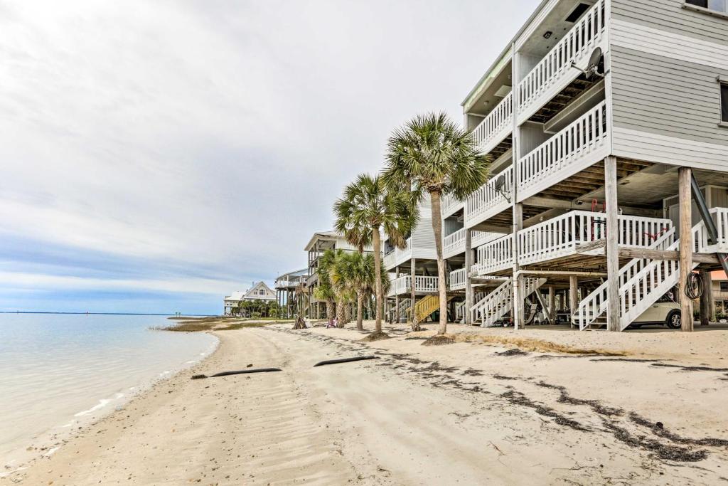 a beach in front of a building with palm trees at Waterfront Escape with Balcony on Shell Point Beach! in Panacea