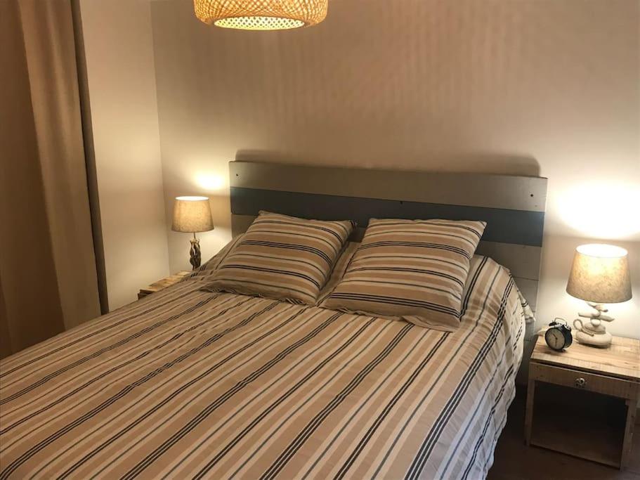 a bedroom with a bed with two lamps and two tables at Winnipeg in Colombiers-sur-Seulles