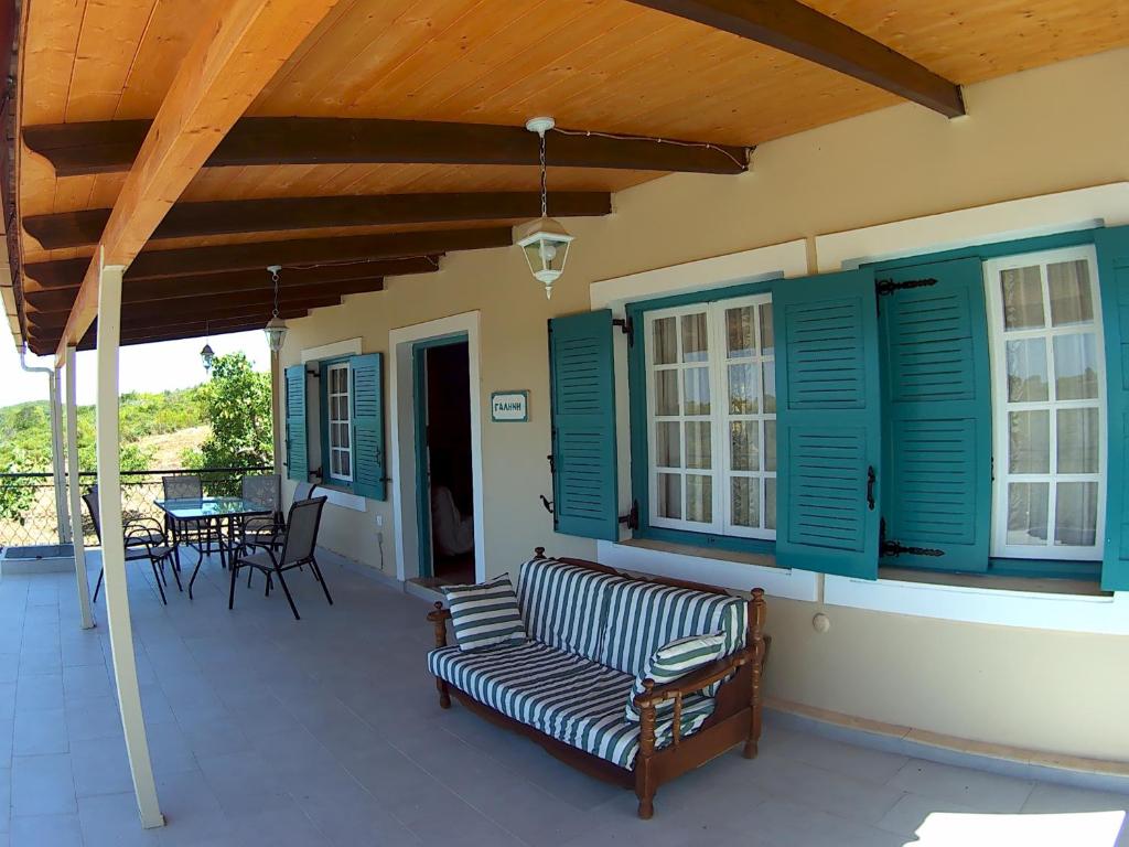 un porche con persianas verdes y un sofá en el patio en Villa “Serenity”, en Agios Leon