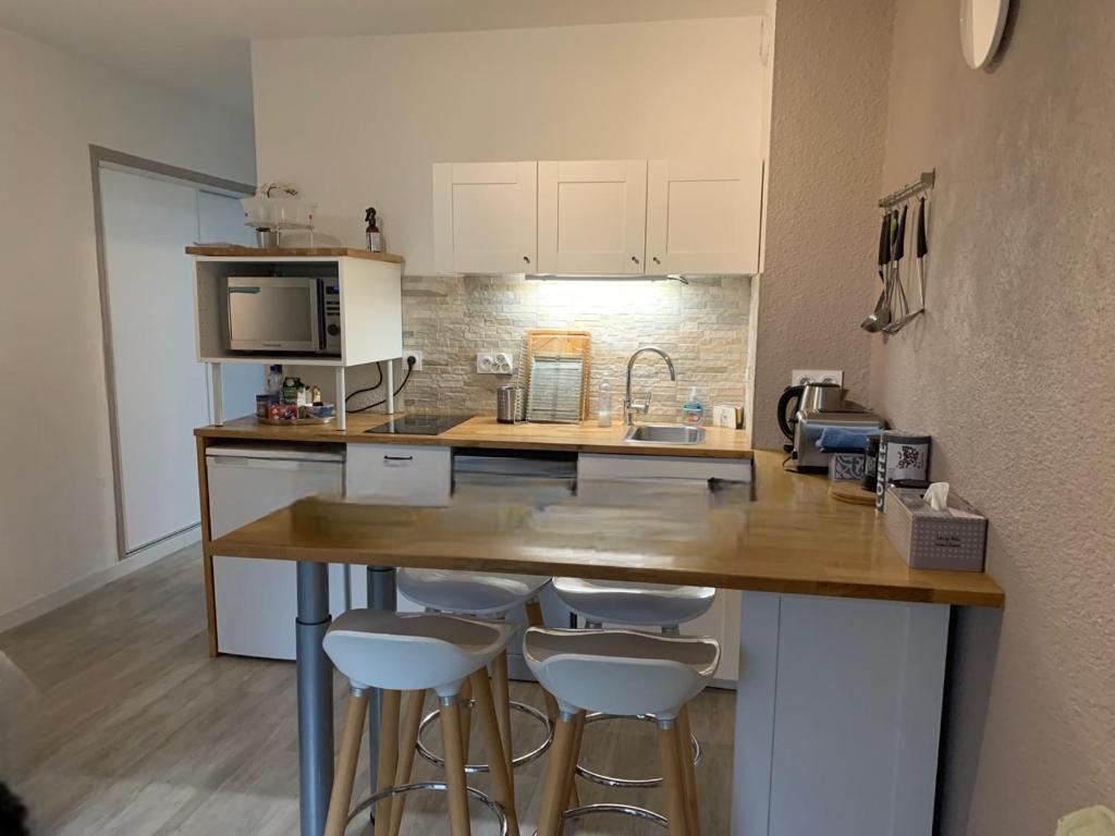 a kitchen with a counter and bar stools in a room at Le Refuge Marin in Courseulles-sur-Mer