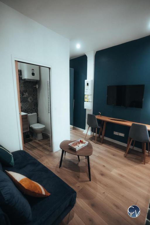 salon z kanapą i stołem w obiekcie Charmant studio rénové - Proche centre ville w mieście Nîmes