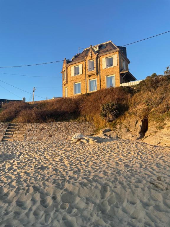 uma casa situada no topo de uma colina ao lado de uma praia em Villa Sainte-Anne - Ploemeur em Ploemeur