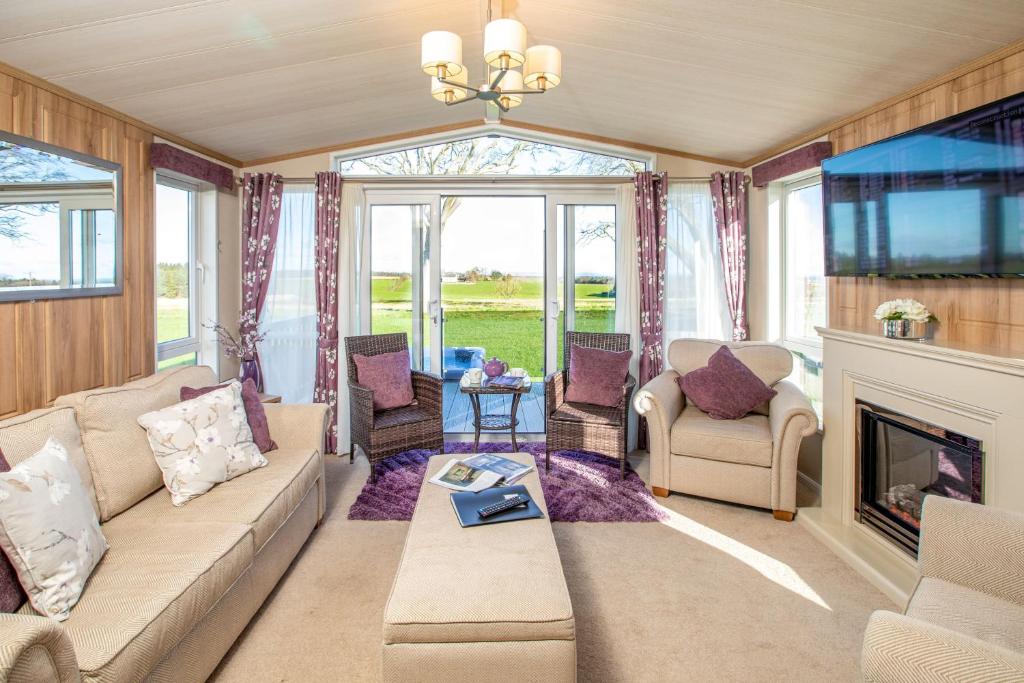 een woonkamer met een bank en een open haard bij Stewarts Resort Lodge 30 in St Andrews