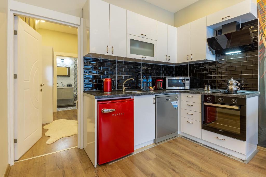 a kitchen with white cabinets and a red refrigerator at BayMari Suites Plus Florya in Istanbul