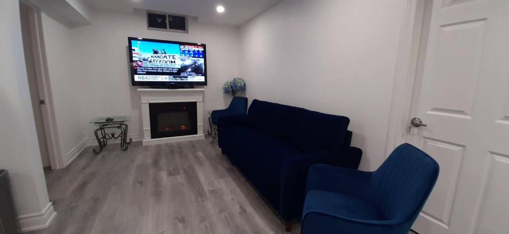 a living room with two blue chairs and a tv at 2 Bedrooms 2 washrooms 2 parking spots Basement Apartment in Newmarket