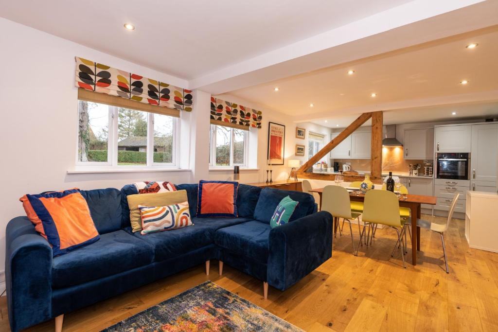 a living room with a blue couch and a kitchen at The Granary, Cretingham in Woodbridge