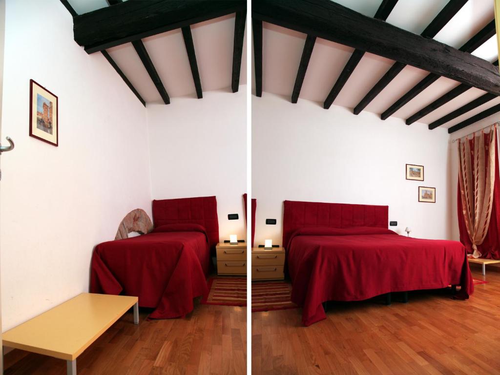 2 camas en una habitación con paredes blancas y sábanas rojas en Il Sipario, en Ferrara