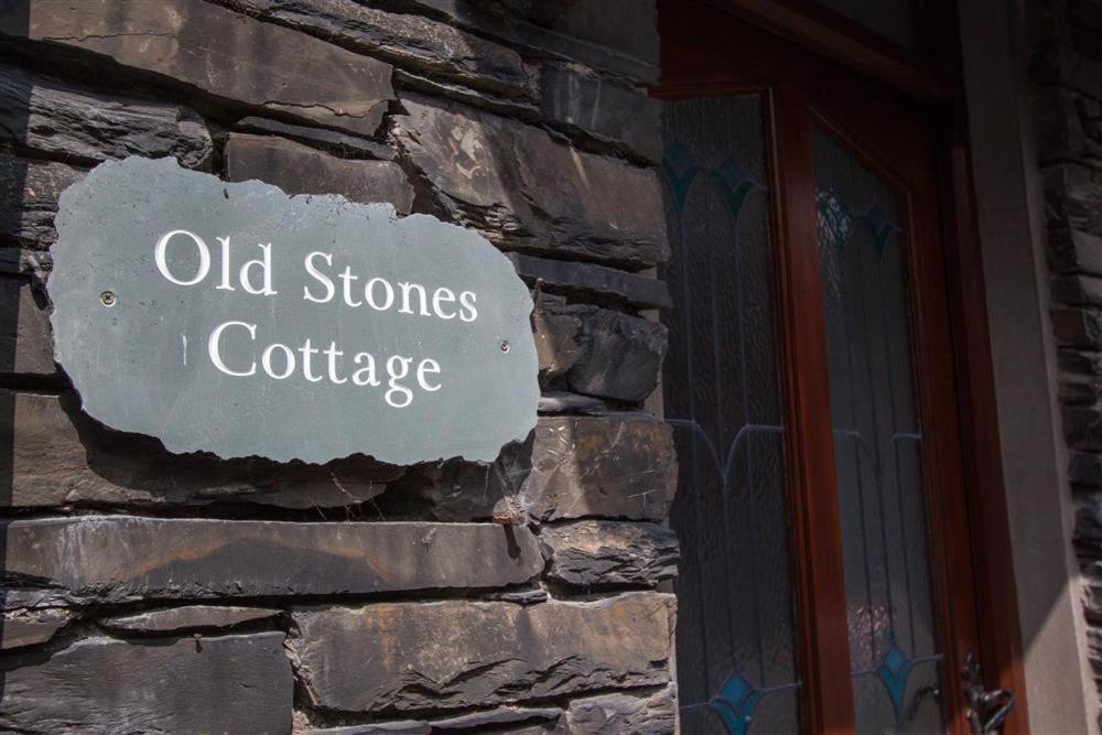 Old Stones Cottage في آمبيلسايد: جدار حجري مع علامة تقرأ الحجارة القديمة i cottage