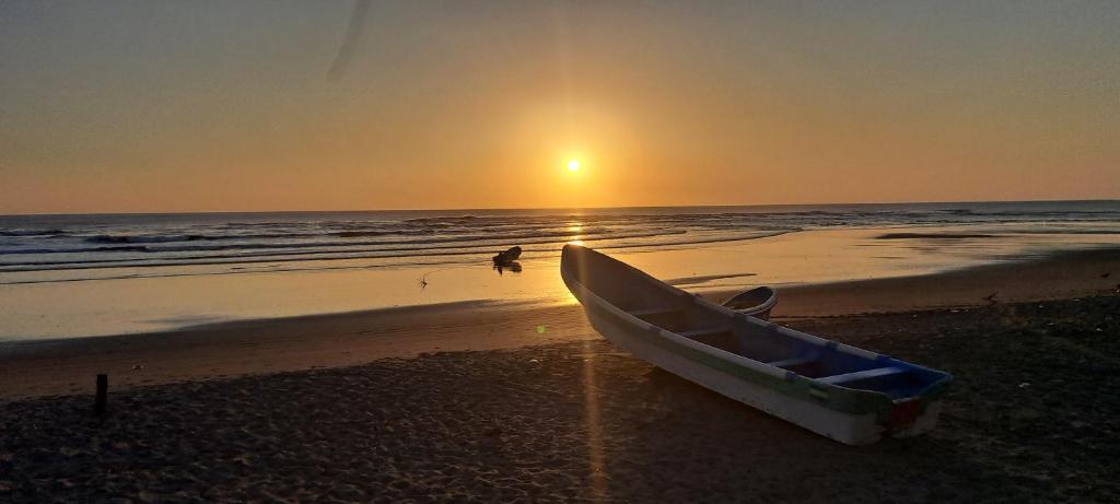 a boat sitting on the beach with the sunset at Playa San Diego Beachfront Rentals in Managua