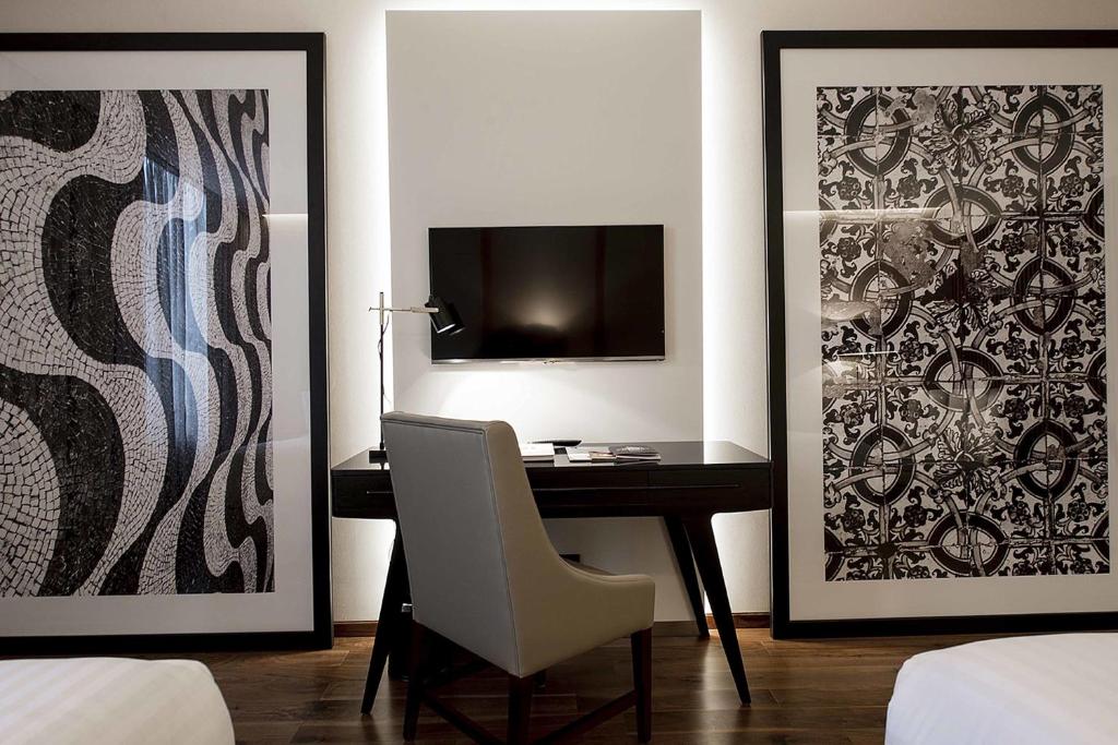 A compact in-room desk positioned beneath a television between two large artworks.