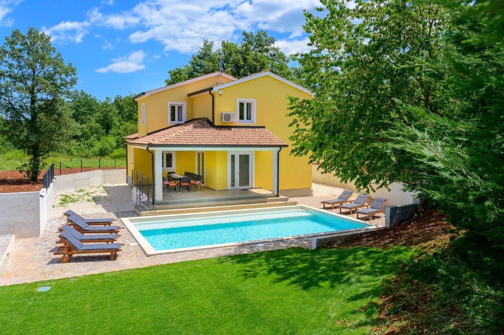 een geel huis met een zwembad in een tuin bij Villa Dada, Žminj, Istria in Žminj