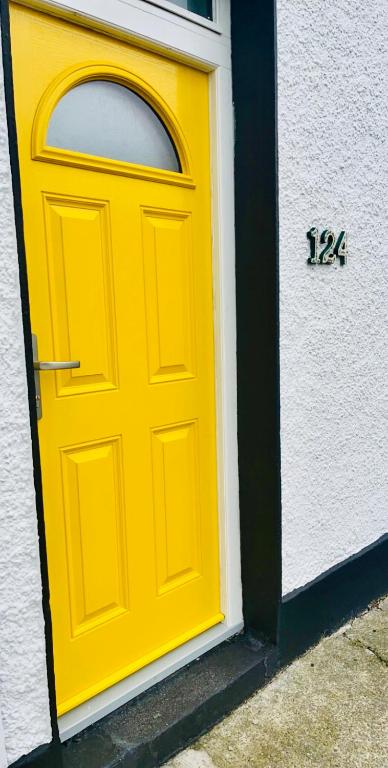 Eine gelbe Tür auf einem Gebäude mit einer Uhr drauf. in der Unterkunft The Yellow Door in Castleisland