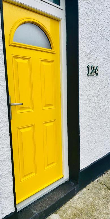 a yellow door on a building with a clock on it at The Yellow Door in Castleisland