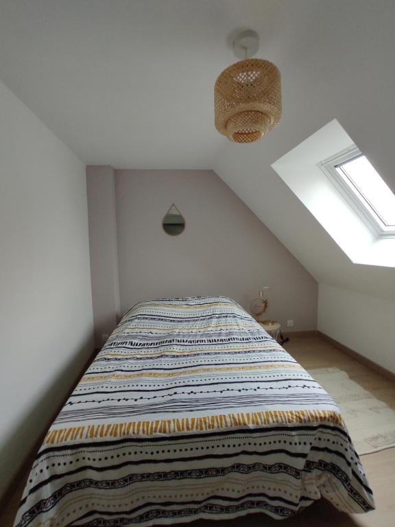 Un dormitorio con una cama con una manta. en La Petite Chaume en Châteauroux