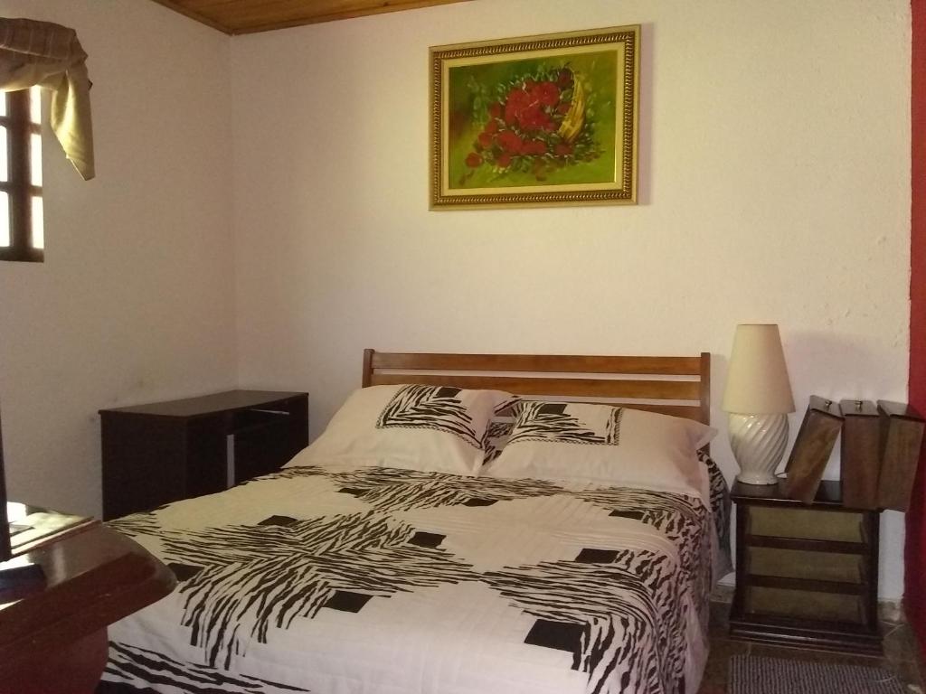 1 dormitorio con 1 cama y una foto en la pared en Casa da Dine-sem café-suite-quadruplo fundos, en Campos do Jordão