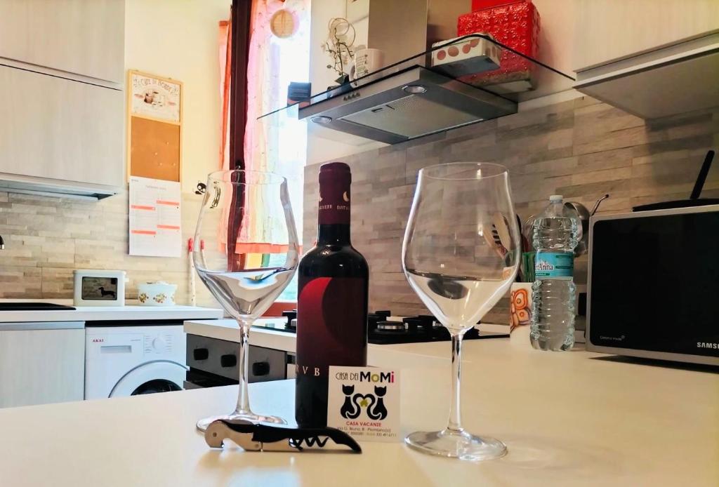 皮昂比諾的住宿－Casa dei MoMi，柜台上的一瓶葡萄酒和两杯酒杯
