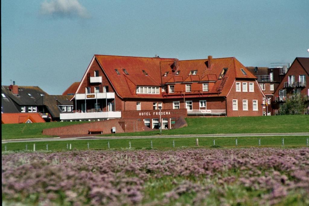 un gran edificio de ladrillo frente a una casa en Hotel Fresena en Baltrum