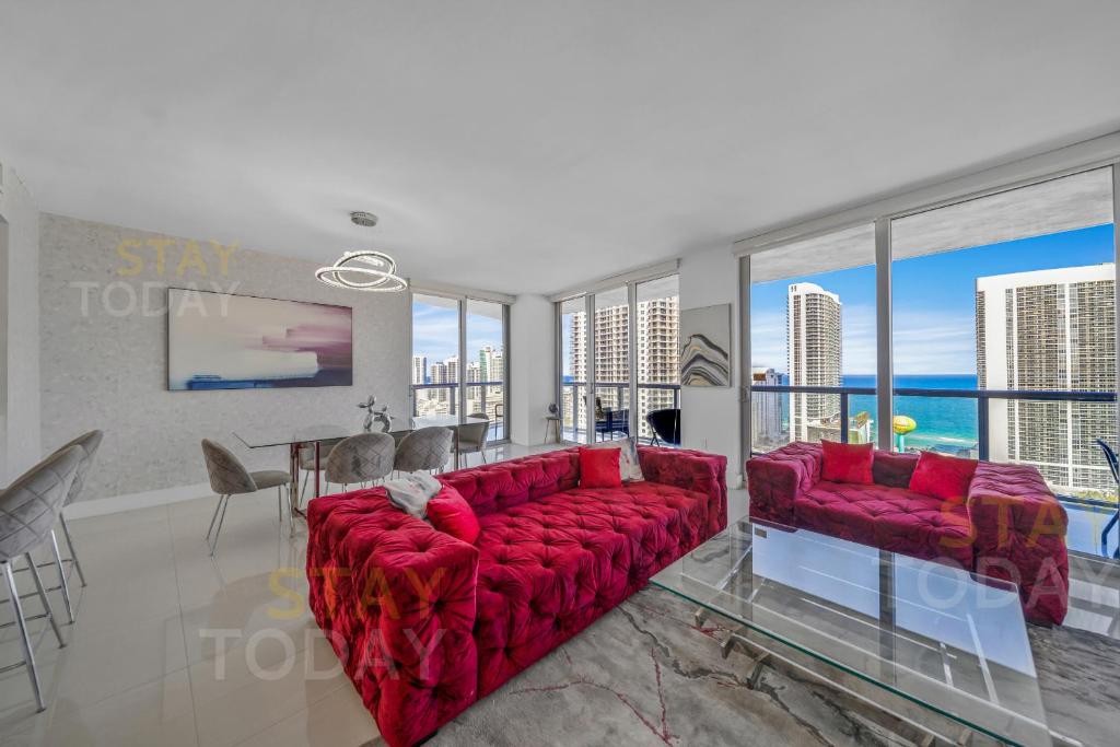 a living room with a red couch and a table at BeachWalk Resort - VIP TOWER #2802 - OCEANVIEW UNIT 3 BEDROOM & 3 BATHROOM in Hallandale Beach