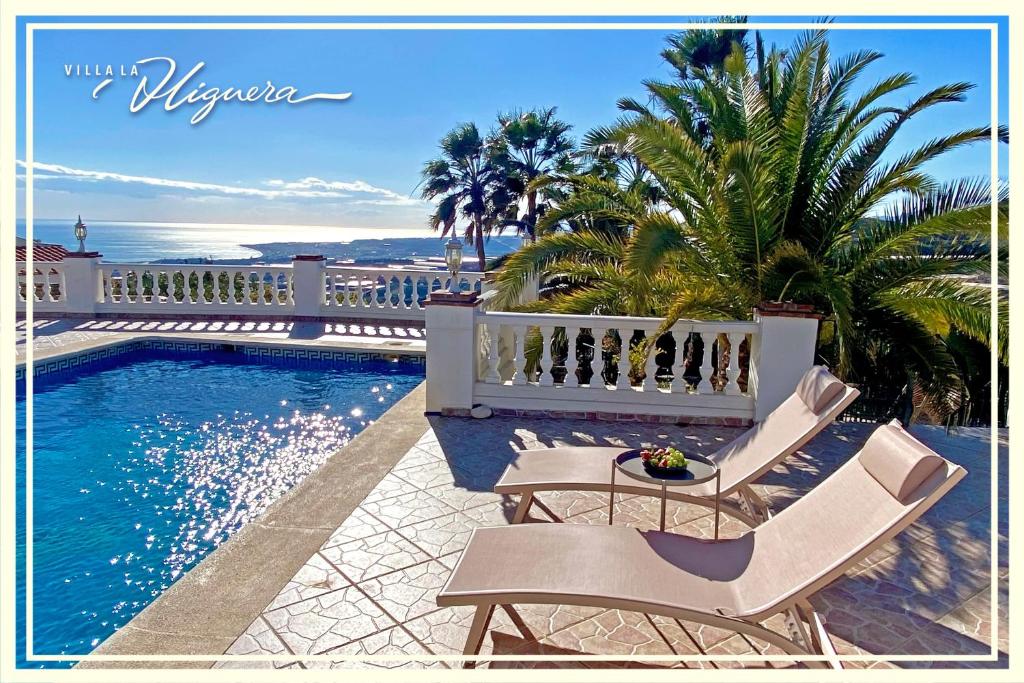 una piscina con due sedie e l'oceano di Villa La Higuera a Sayalonga