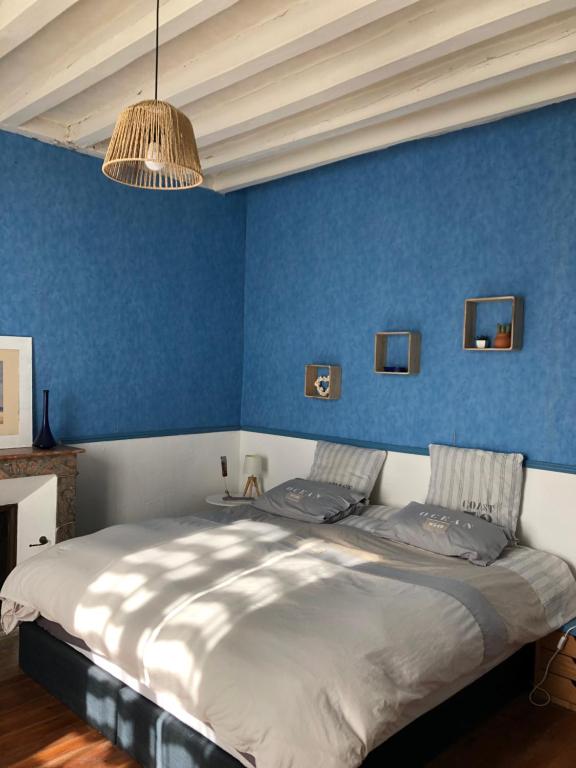 um quarto com paredes azuis e uma cama grande em Maison de famille em Saint-Mars-dʼOutillé