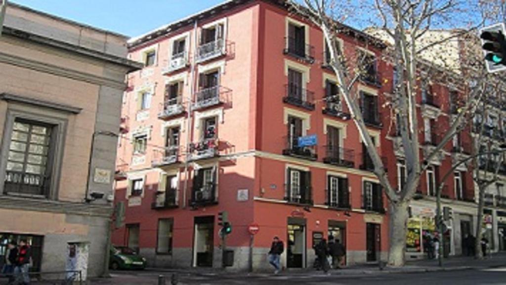 a red building on a street with people walking in front of it at Pensión Mollo in Madrid