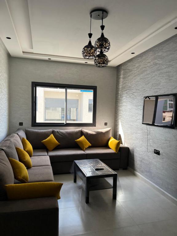a living room with a couch and yellow pillows at Appartement familial Soleil et Mer à 150m de la Plage de Mehdia in Plage de Mehdia