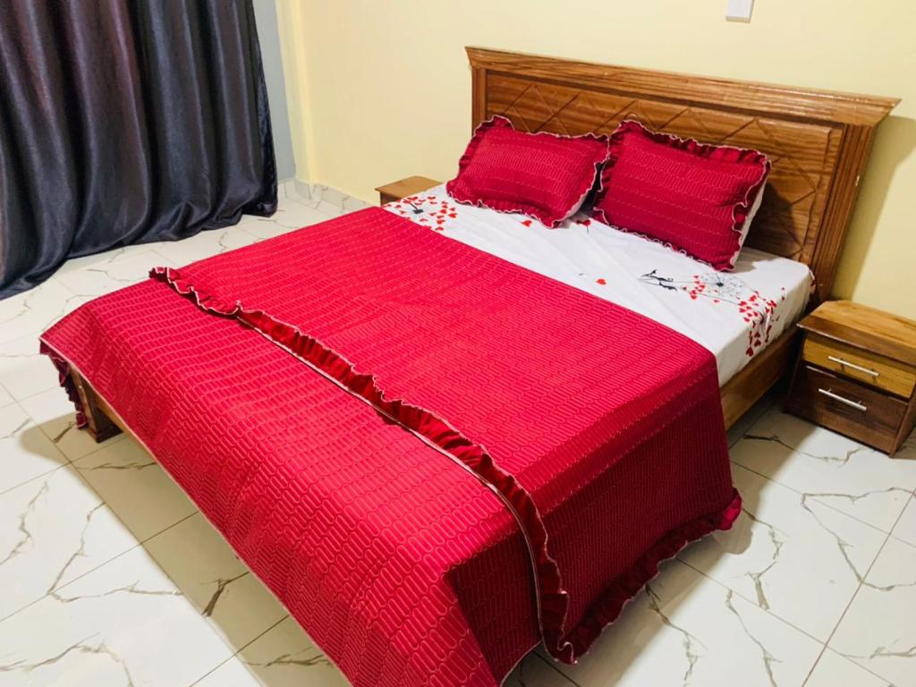 a large bed with red sheets and red pillows at Blue Sky in Kigali