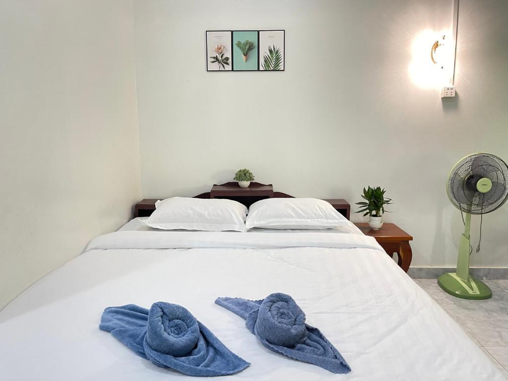 a white bed with two blue towels on it at Mother’s House in Battambang