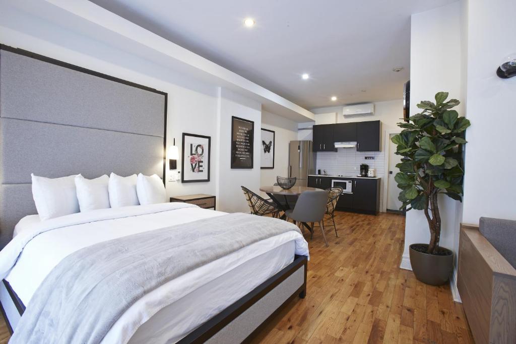 a bedroom with a large white bed and a kitchen at hotel & spa Carré Saint-Louis in Montreal