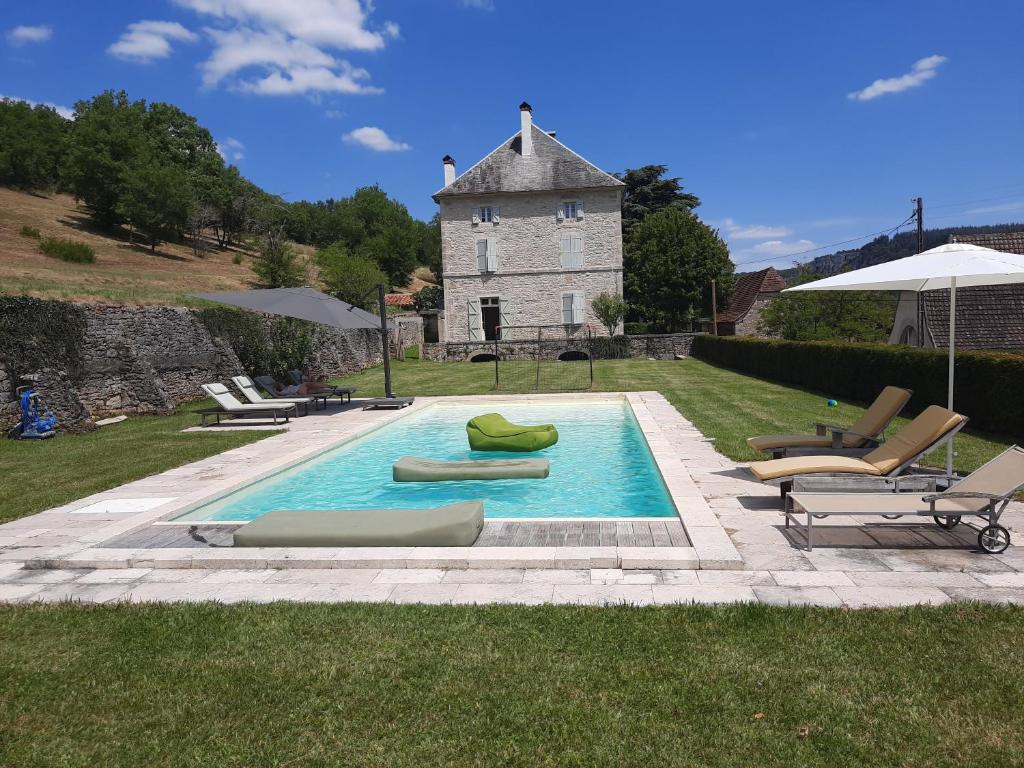 une piscine avec des chaises longues et un bâtiment dans l'établissement Vakantiehuis Domaine de Nazac, à Saint-Sulpice