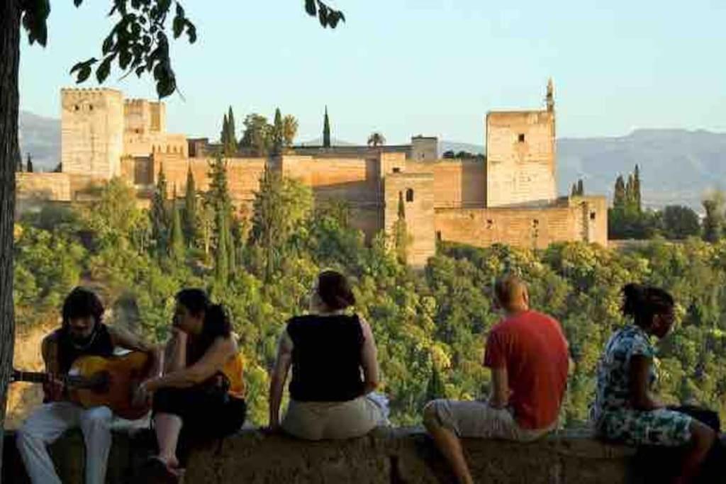 un groupe de personnes assises sur un mur qui regarde un château dans l'établissement Granada, ciudad encantada, à Cájar