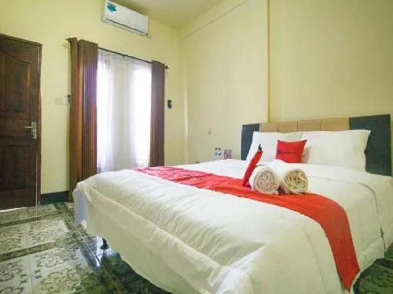 a bedroom with a large white bed with a red blanket at MURSYS PLACE in Kuta Lombok
