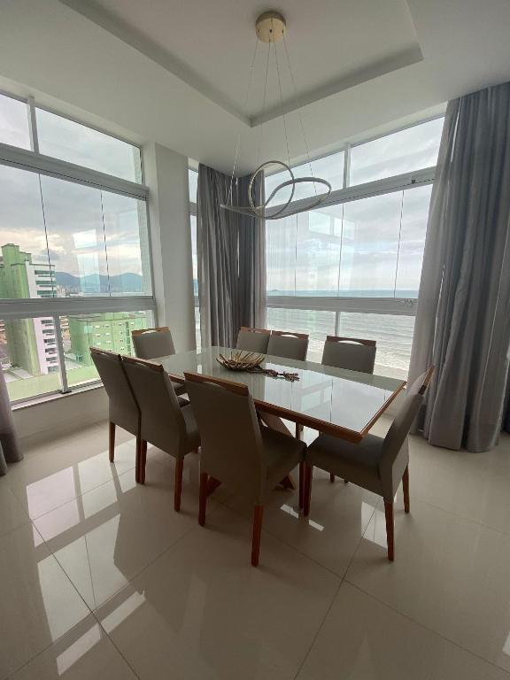 uma sala de jantar com mesa e cadeiras e o oceano em Apto 3 Suítes para famílias com vista para o mar em Itapema