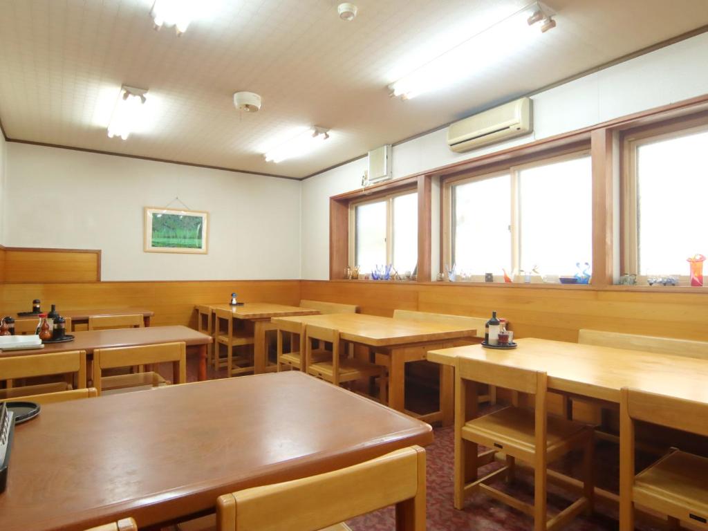 an empty restaurant with wooden tables and windows at Hakuraiso in Matsumoto