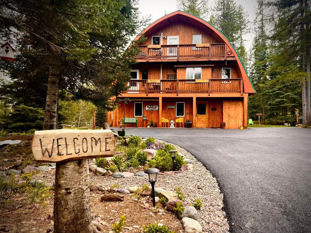 a welcome sign in front of a wooden house at Moss Mountain Inn in Columbia Falls