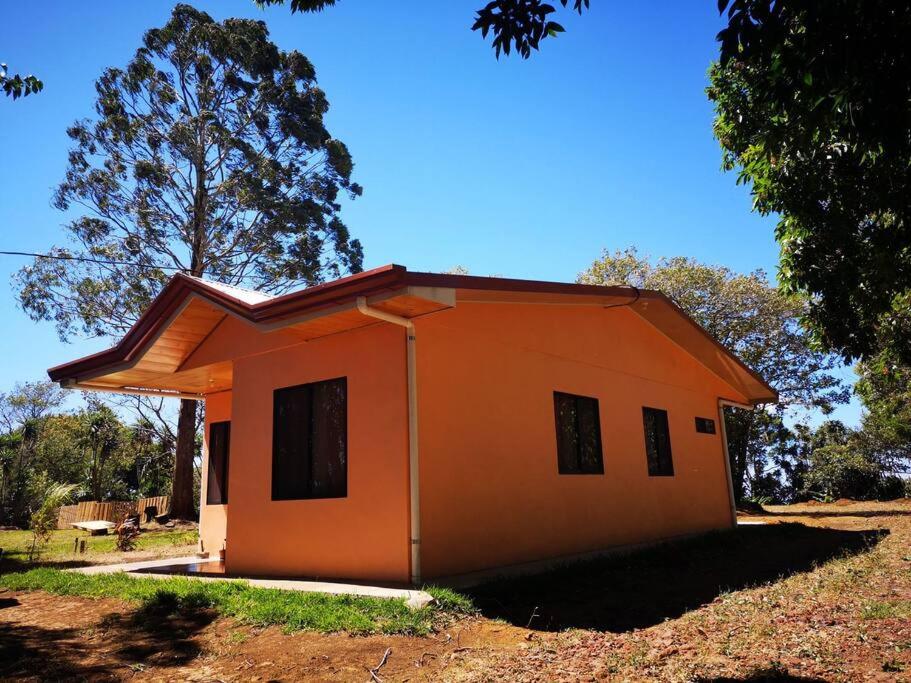 mały pomarańczowy dom pośrodku pola w obiekcie Casa del Eucalipto w mieście Sabana Redonda