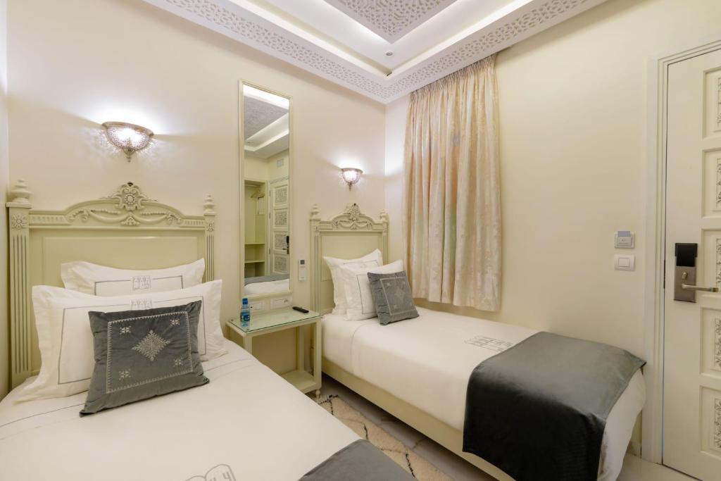 マラケシュにあるHOTEL RIAD CHAMIのベッドルーム1室(ベッド2台、鏡付)