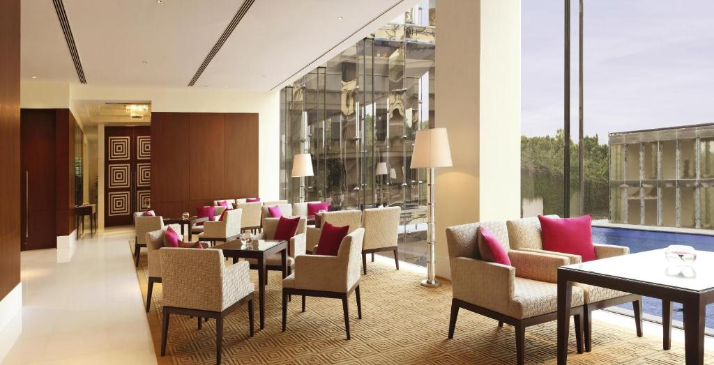un comedor con mesas, sillas y ventanas en The Oberoi Gurgaon, en Gurgaon