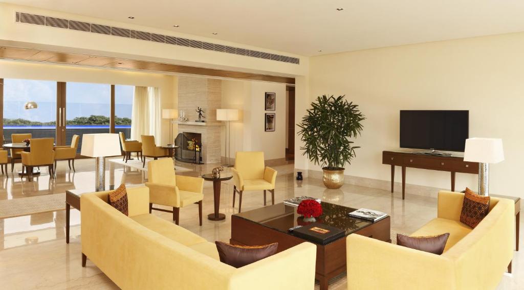 sala de estar con sillas amarillas y TV en The Oberoi Gurgaon, en Gurgaon