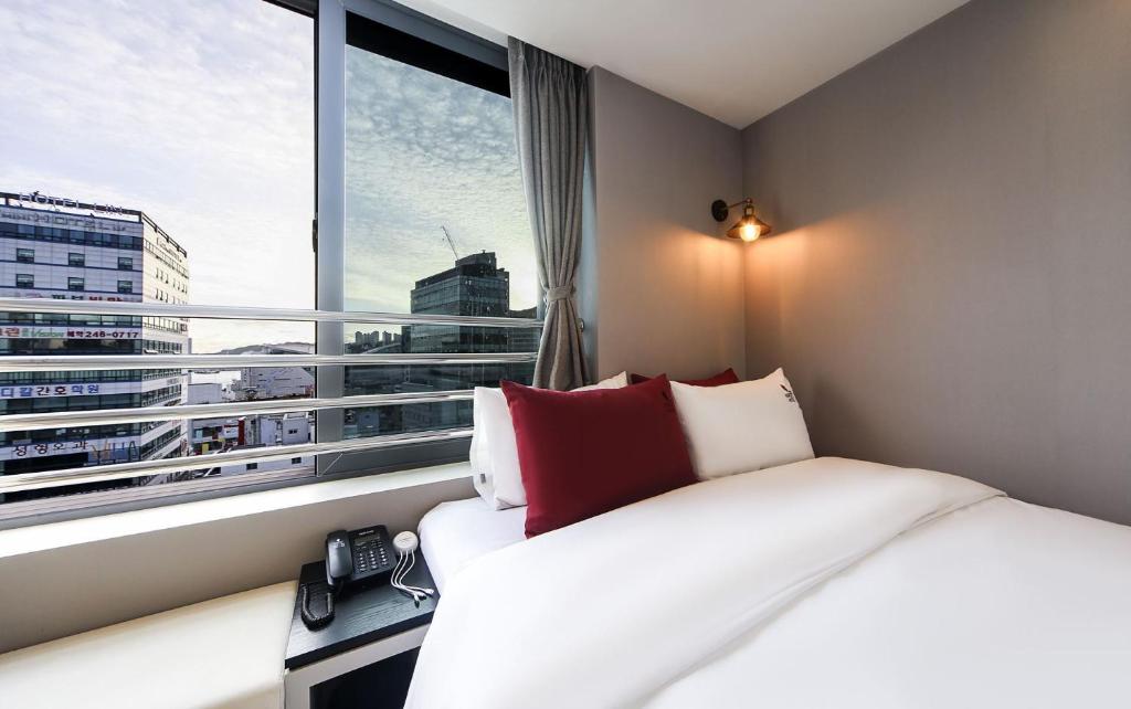 a hotel room with a bed and a large window at Maron Hotel Nampo in Busan