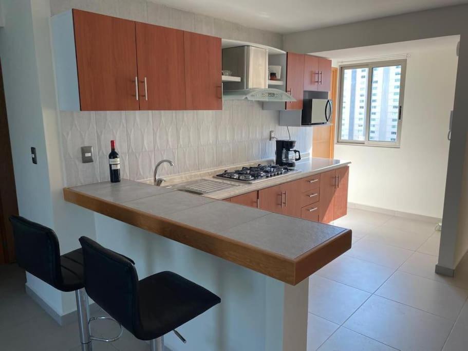 a kitchen with a counter and a sink with a bottle of wine at Palermo - Acapulco in Acapulco