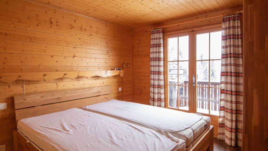 Bett in einem Holzzimmer mit Fenster in der Unterkunft Toggi OG in Bettmeralp