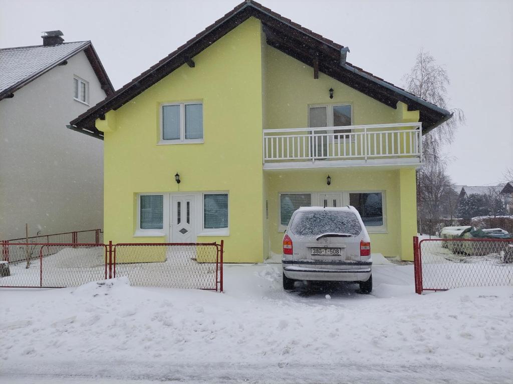 ein gelbes Haus mit einem Auto im Schnee in der Unterkunft Apratmani Ivić in Kupres