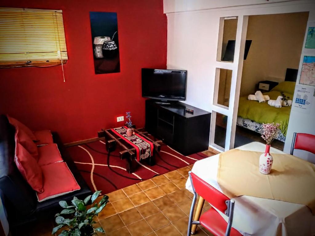 a living room with red walls and a couch and a table at Departamento Urbano in San Carlos de Bariloche