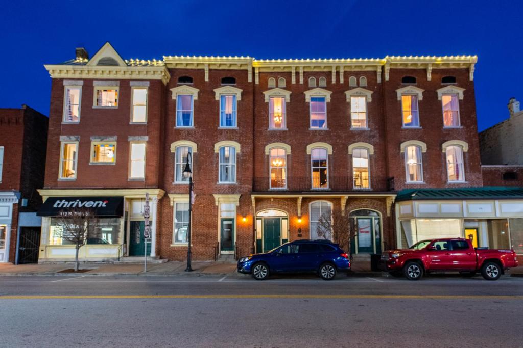 two cars parked in front of a large brick building at The Woodford Hotel in Versailles